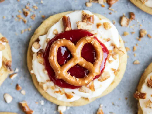 These Strawberry Pretzel Cookies take everything you love about the classic potluck dessert, and turn it into a fun, bakery-style cookie. The cookies start with a soft brown sugar pretzel filled cookie base, topped with
